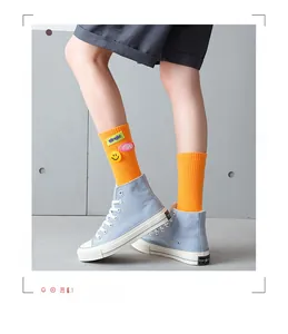 Detail of bright orange ribbed socks with letter patches paired with blue canvas shoes