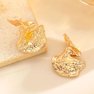 Detailed view of golden textured metal earrings with artistic hammered surface on stone