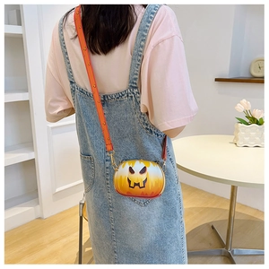 Close-up of orange pumpkin-shaped crossbody bag with chain strap worn by a model