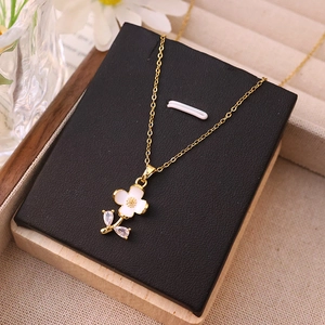 Elegant gold necklace with white flower pendant and sparkling zircon on a black display card