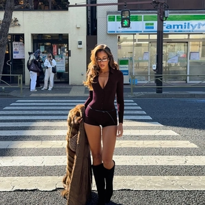 Street style shot of a dark brown V-neck jumpsuit with a black belt on a city crossing