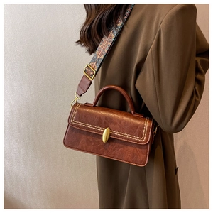 Detail of vintage brown leather crossbody bag with studded flap and ethnic patterned strap