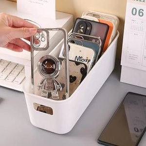 Close-up of a white desktop organizer box showing storage for astronaut phone cases