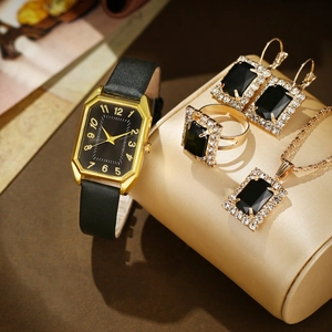 Close-up of elegant gold rectangular watch and matching black gemstone jewelry set