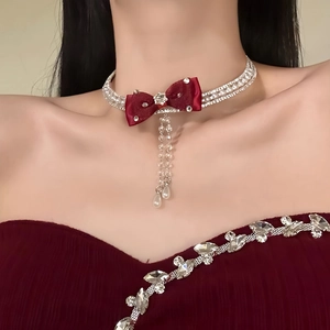 Detail of choker with velvet red bow, shimmering rhinestones, and elegant pearl tassels