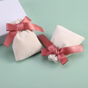 Macro shot of beige velvet jewelry pouch with soft dusty pink satin bow tie detail