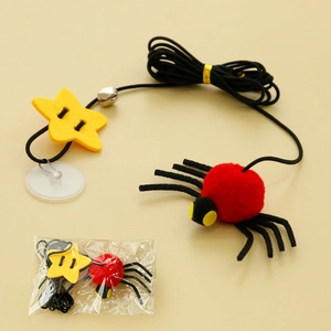 Detail of hanging cat toy featuring a red plush spider and star with bell on elastic cord