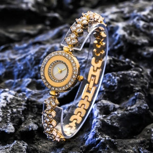 Luxury gold women's quartz watch with full diamond setting on a dark textured rock