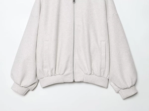 Close-up of soft gray bomber jacket showing metal zipper and ribbed cuffs detail