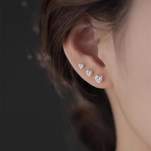 Close-up of three different sized 925 sterling silver heart-shaped stud earrings set