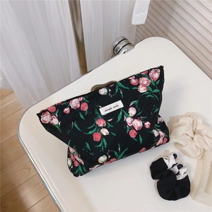 Detailed view of black floral makeup bag with pink tulips on a white tray