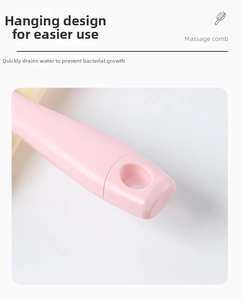 Detail of pink massage comb handle featuring a hanging hole for easy storage and drying