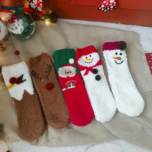 Cozy coral fleece Christmas socks with festive 3D character dolls in a warm holiday setting
