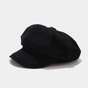Close-up of black corduroy newsboy cap showing detailed ribbed texture and octagonal shape