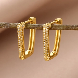 Macro detail of 18k gold-plated rectangular earrings with white zircon on a branch