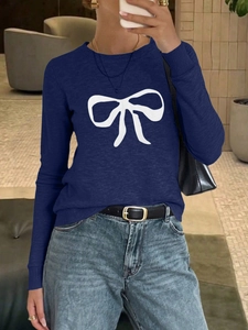 Detailed close-up of dark blue knit sweater featuring a white bow print and round neck