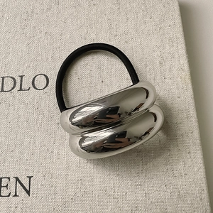 Macro shot of silver wave metal elastic hair tie with mirror polish finish on linen background