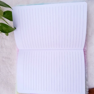 Detailed view of the lined inner pages of a plush rainbow unicorn notebook with green leaf décor