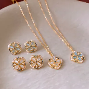 Elegant floral jewelry set with white opal petals and blue gems on a ceramic tray