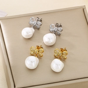 Detail of gold and silver bow earrings featuring sparkling zircons and baroque pearls