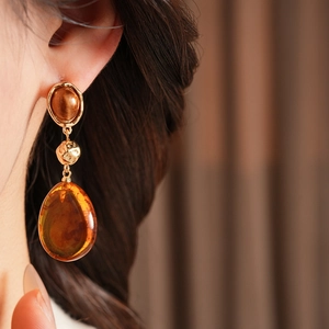 Close-up detail of vintage waterdrop earrings with amber resin pendant and hammered gold bead