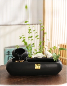 Zen ceramic water fountain detail featuring two porcelain ducks and gold calligraphy on matte base