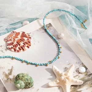 Blue turquoise bead necklace with gold accents on a beach themed background