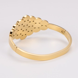 Close-up of golden irregular honeycomb scale design on stainless steel bangle