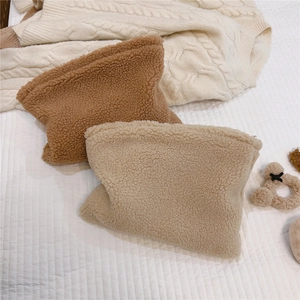 Close-up of fluffy teddy fleece cosmetic bags in brown and white on a soft textured backdrop