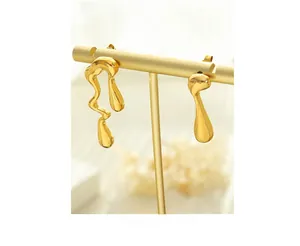 Detalle de pendientes asimétricos bañados en oro de 18 quilates con acabado metálico