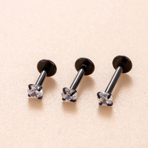 Tre piercing labret neri in acciaio con zirconi chiari da 3mm in uno scatto di dettaglio