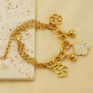 Détail d'un bracelet double chaîne plaqué or 18k avec fleur évidée et cristaux brillants