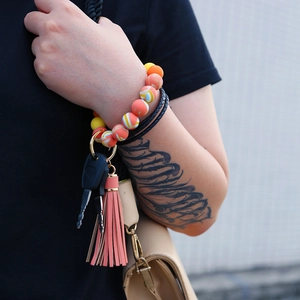 Detail of beaded silicone wristlet keychain with leather tassel on model wrist