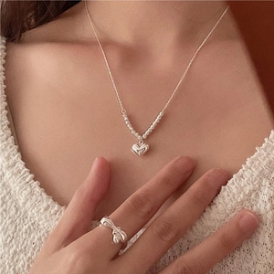 Minimalist 925 sterling silver heart necklace and textured ring set on a female model