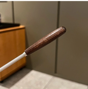Detail of ergonomic dark wood handle and durable stainless steel spiral spring whisk