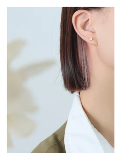 Close-up of gold-plated stud earring with clear zircon inlay on a female model