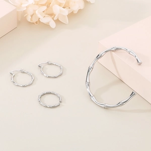 Macro shot of silver bamboo style jewelry set including earrings, ring and cuff bracelet