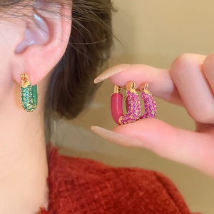 Detail view of green and rose red pavé zircon U-shaped hoop earrings with gold base