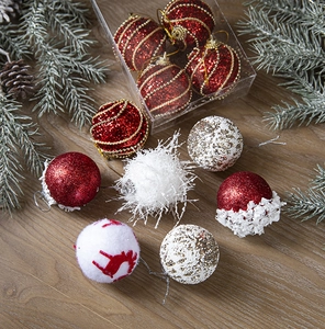 Detail of glitter and flocked Christmas balls on wooden table with pine branches