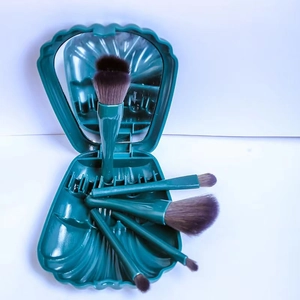 Green shell-shaped makeup brush set with five brushes and a built-in mirror storage case