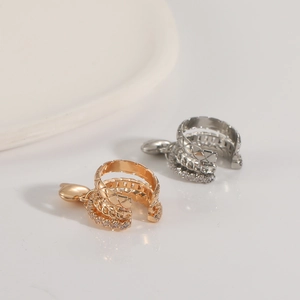 Detail of layered gold and silver ear cuffs with zircon stones and heart pendants