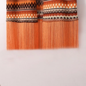 Détail d'un gilet bohème en maille avec motifs contrastés orange et longues franges à glands