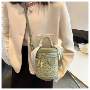 Detail of green cylinder handbag with embossed pattern and silk scarf handle