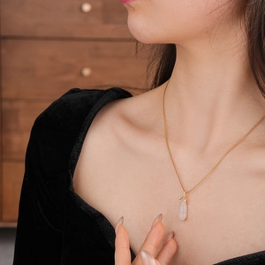 Detail of gold-plated chalcedony eggplant necklace on model with black velvet background