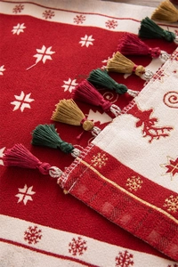 Macro view of Christmas table runner fabric with snowflake pattern and colorful tassels