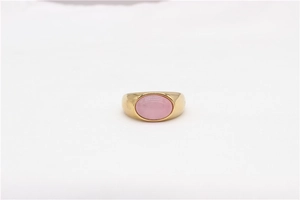 Detailed view of vintage gold ring featuring a pink oval gemstone on white background