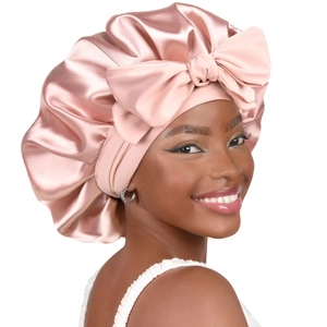 Close-up of pink satin hair bonnet for women featuring a large decorative bow and soft texture
