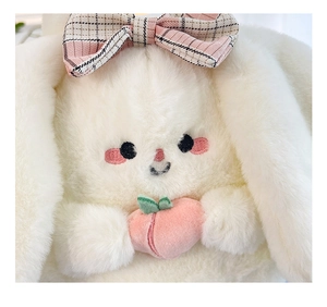 Close-up of plush white bunny toy with pink checkered bow holding a pink peach