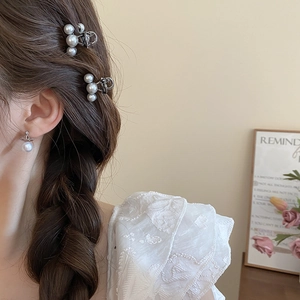 Detail of mini pearl hair claw clip and planet pearl earrings on braided hair