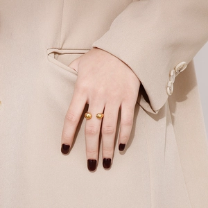 Close-up of a gold minimalist open ring with dual polished spheres on a female finger